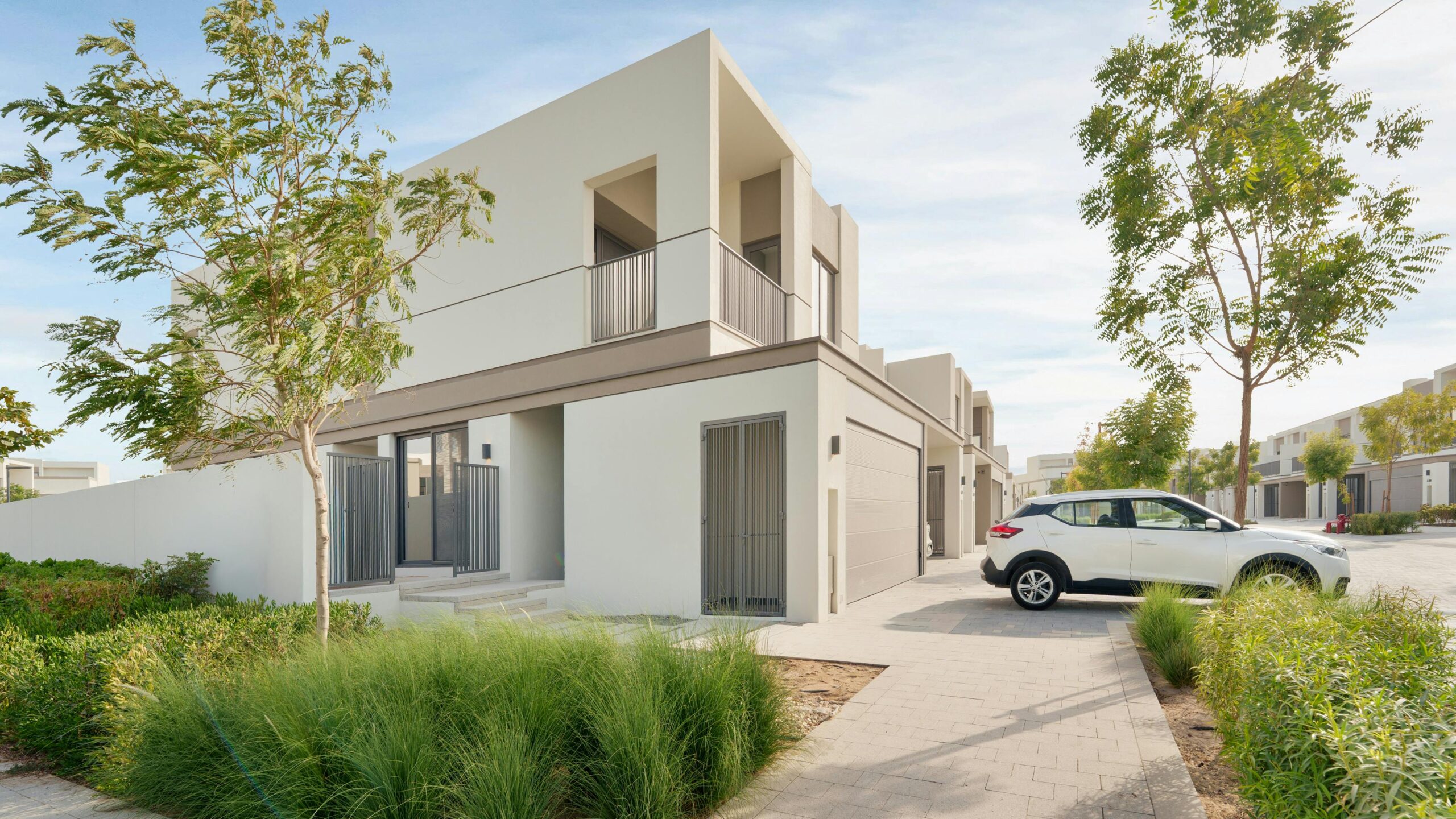 Contemporary villa in Dubai with a parked car, surrounded by lush greenery.
