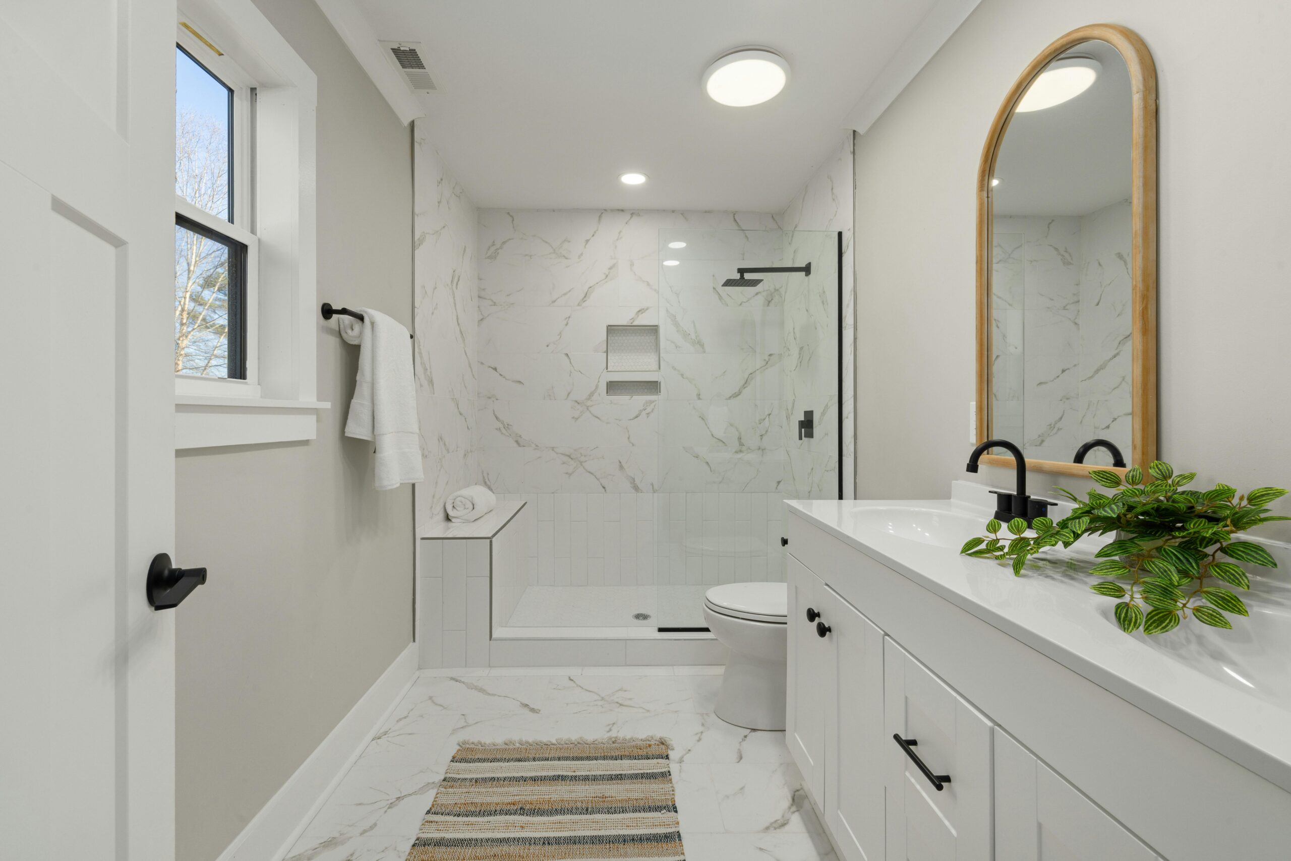 Sunset Haven Bright modern bathroom featuring marble shower, large mirror, and sleek faucets.
